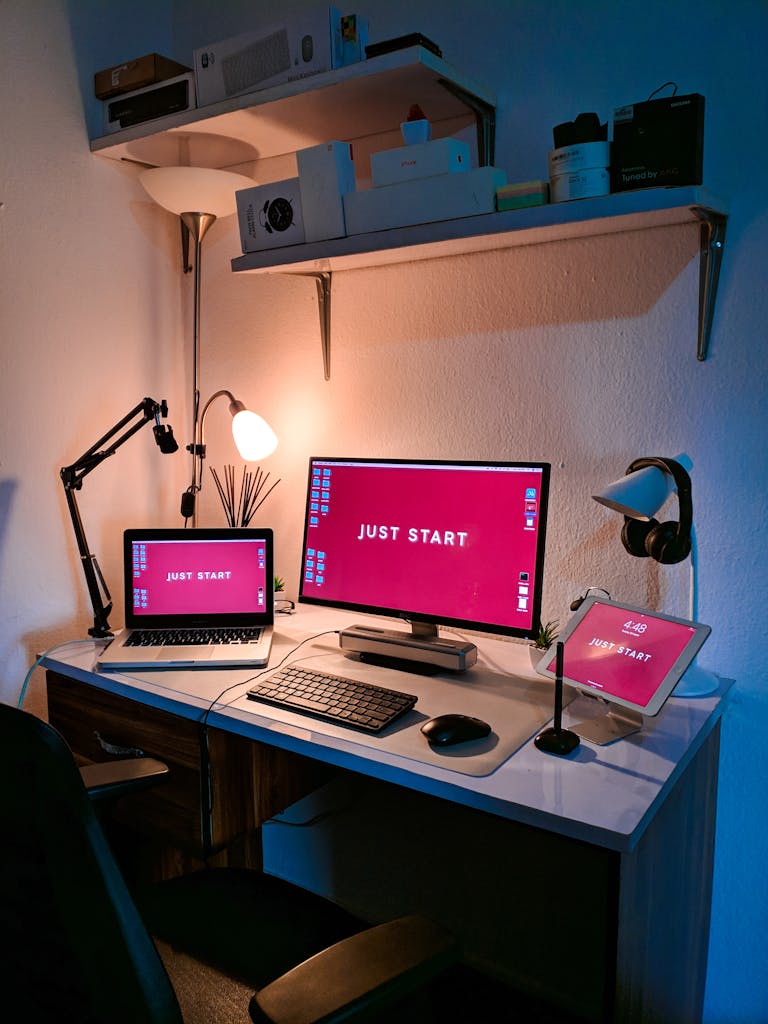 A stylish home office setup featuring a laptop, monitor, and tech accessories on a desk with cozy lighting.