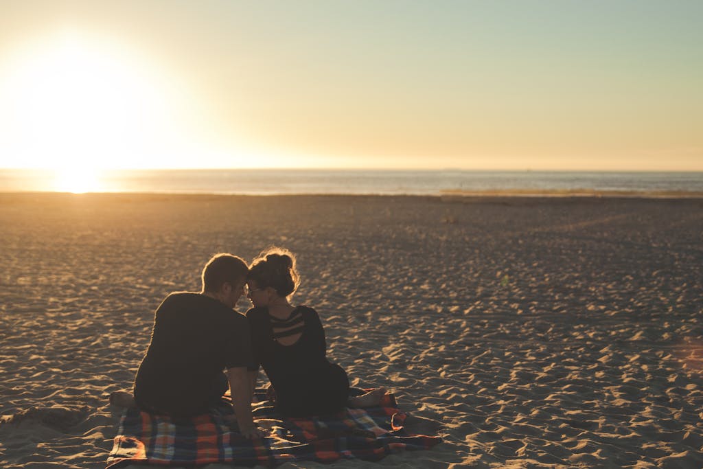 A couple enjoys sunset together on a sandy beach, capturing a moment of love and togetherness. third date tips