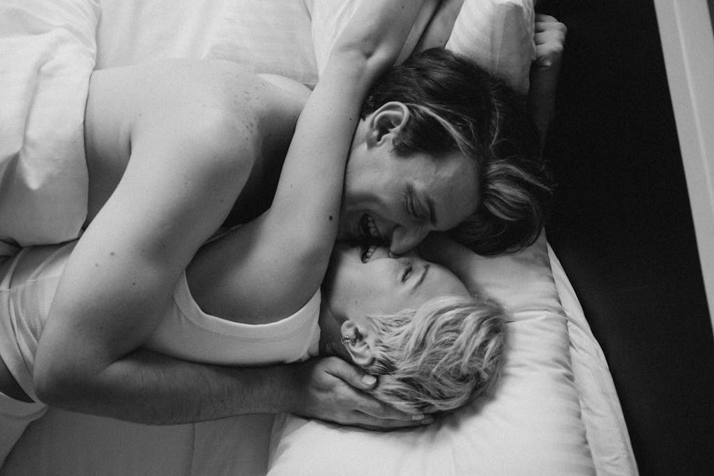 A romantic black and white photo capturing a couple's intimate embrace in bed, highlighting love and connection. sex