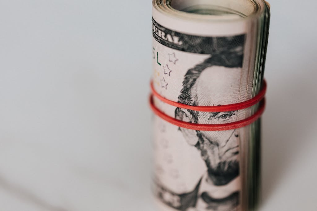 Close-up of a roll of US dollars wrapped with a red rubber band focusing on financial abundance. personal budget