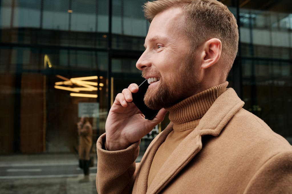 Close-up of a smiling businessman with a beard making a smartphone call outdoors. smart goals and goal setting