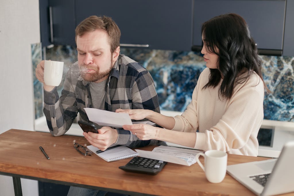 Couple discussing financial documents and budgeting at a kitchen table. saving money. save money