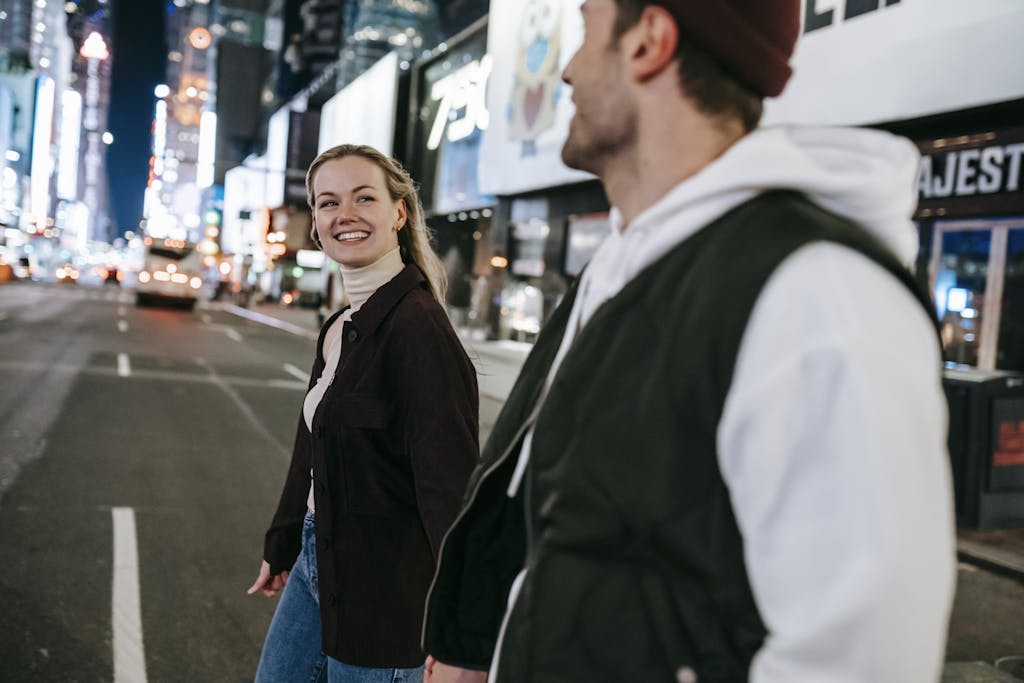 Couple walking and smiling at each other in a brightly lit urban street at night. building stronger connections for a stronger relationship