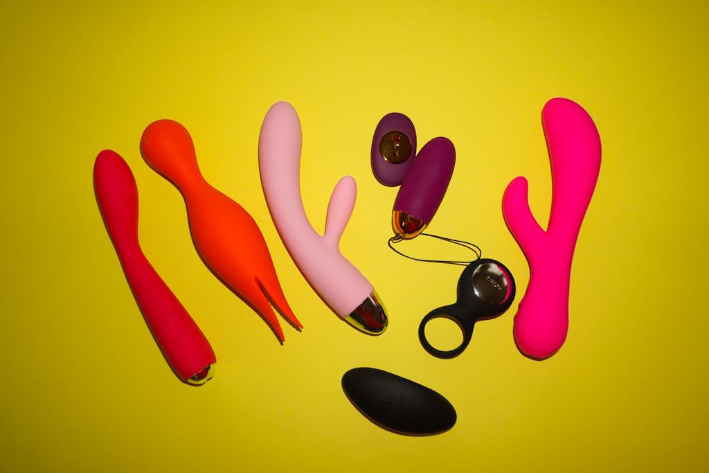 Studio setup showcasing colorful sex toys on a bright yellow background, featuring various shapes and designs. sex toys in relationships