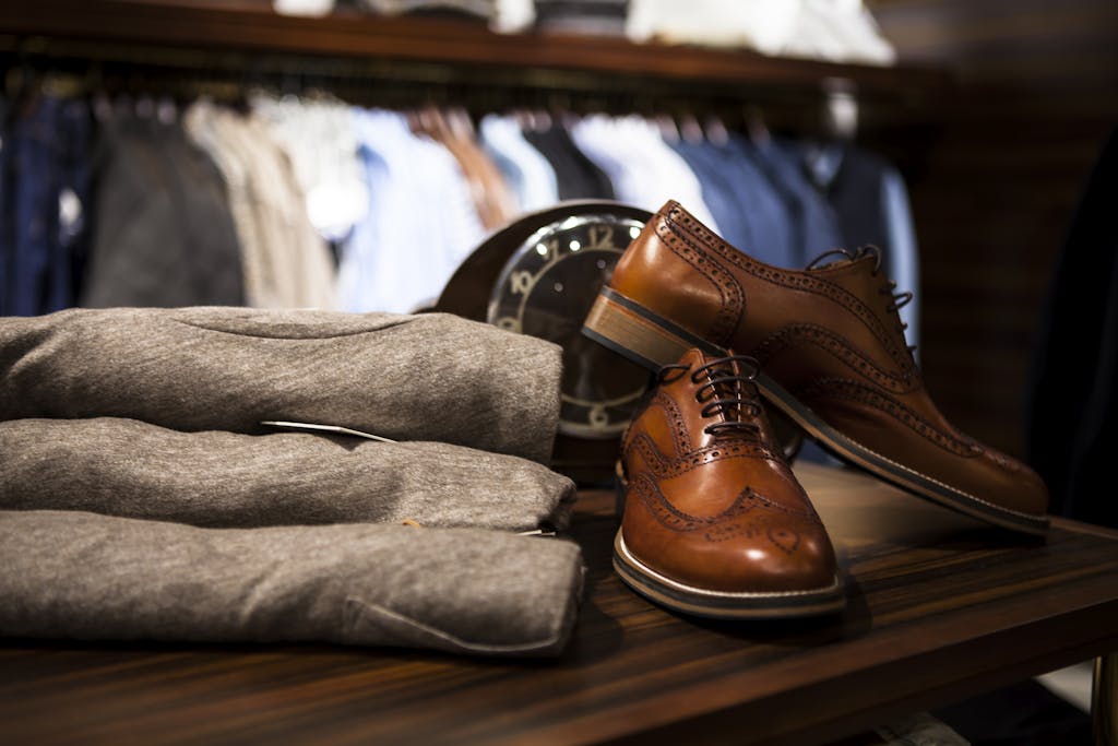 Stylish leather shoes displayed with gray clothing in a chic boutique setting. men's style blog